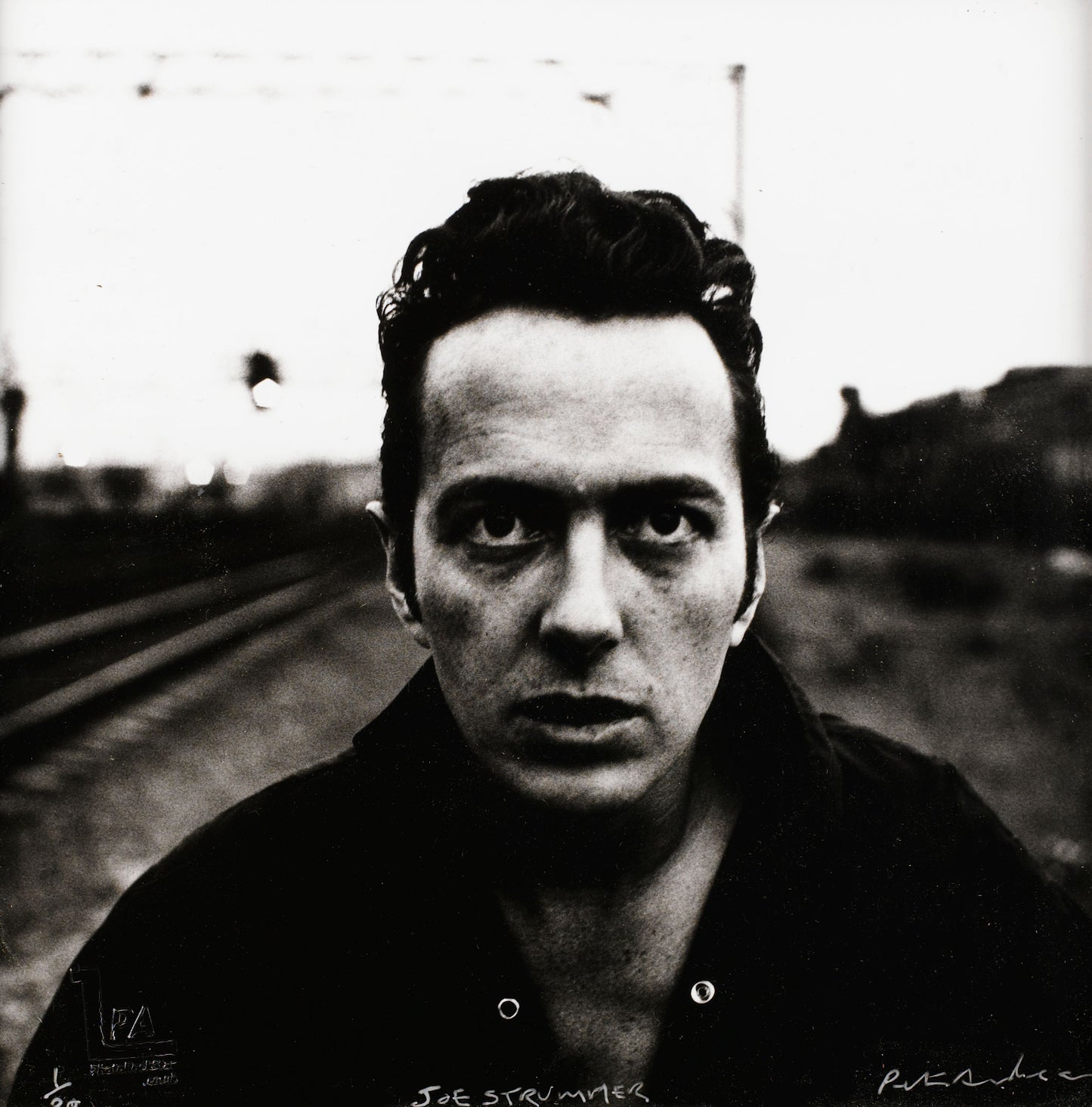 Portrait of Joe Strummer (The Clash) titled 'On the Wrong Side of the Tracks'. Black and white silver gelatin print, hand-printed and signed by Peter Anderson, Shoreditch 1987.