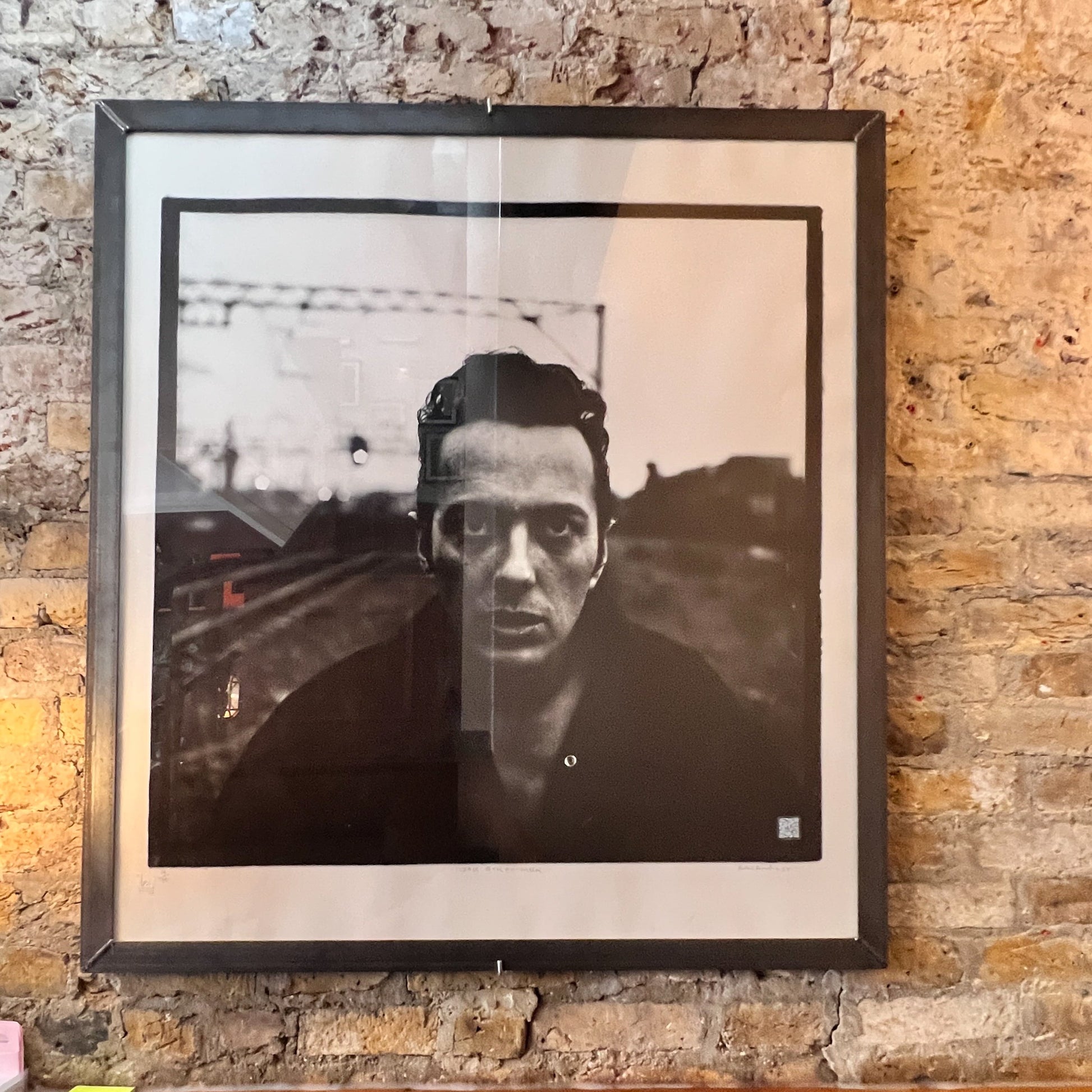 Large square format black and white silver gelatin fibre print of Joe Strummer in Shoreditch 1987 titled Wrong Side of the Tracks, in a welded steel frame by Peter Anderson.