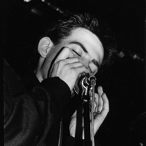 High-contrast black and white silver gelatin live photograph of Robert Smith from The Cure performing at the Marquee Club in Soho 1979 by Peter Anderson.
