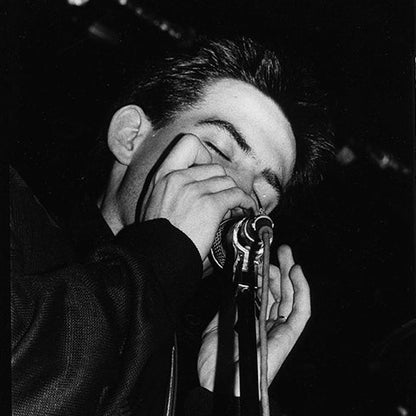 High-contrast black and white silver gelatin live photograph of Robert Smith from The Cure performing at the Marquee Club in Soho 1979 by Peter Anderson.