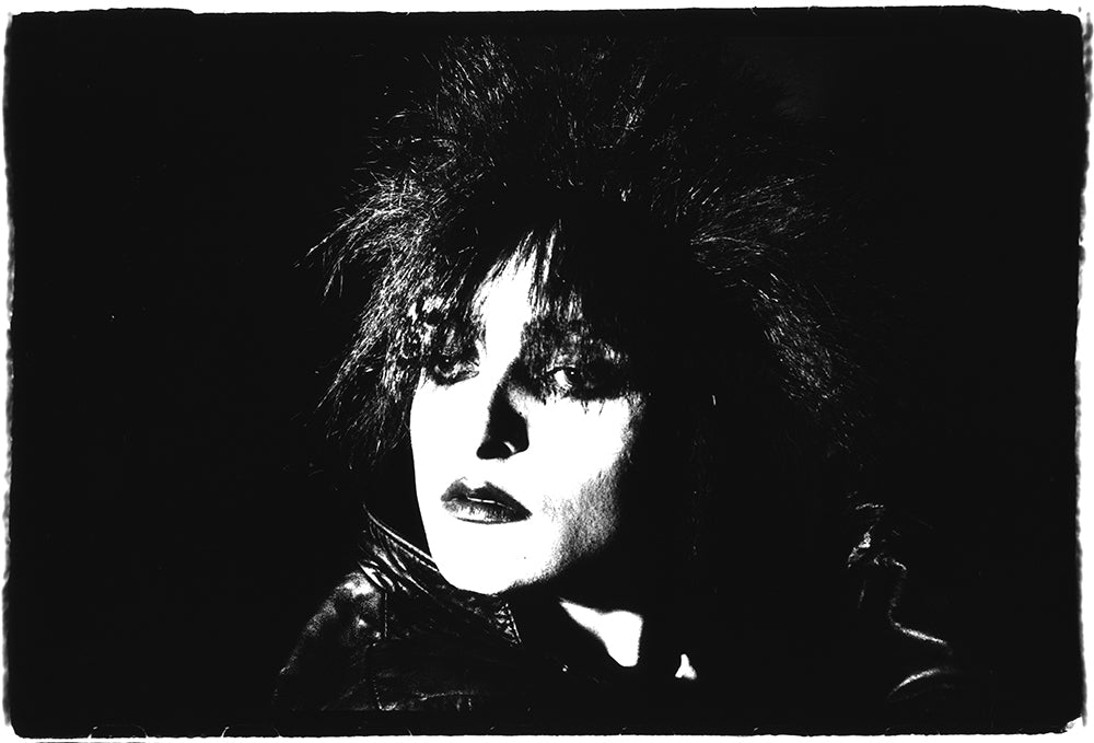 Black and white silver gelatin darkroom live photograph of Siouxsie Sioux performing on stage in Sheffield 1980 titled Firing the Shots by Peter Anderson.