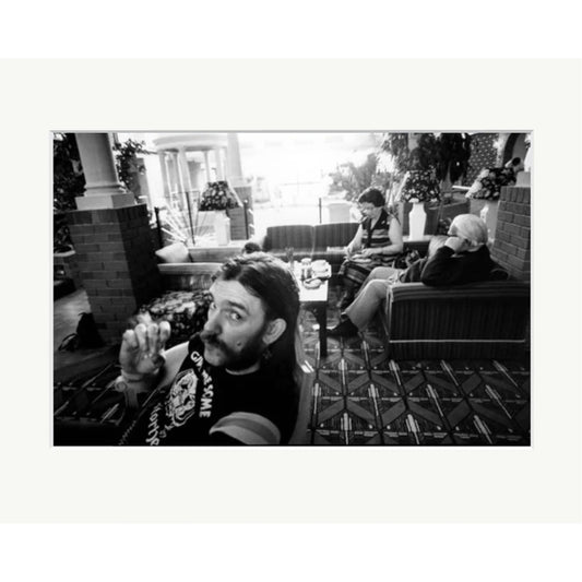 Silver gelatin darkroom print of Lemmy Kilmister from Motörhead, captured by Peter Anderson during breakfast at a Portsmouth Holiday Inn, 1983. The black and white photograph shows Lemmy in the foreground of a hotel lobby with other guests in the background.